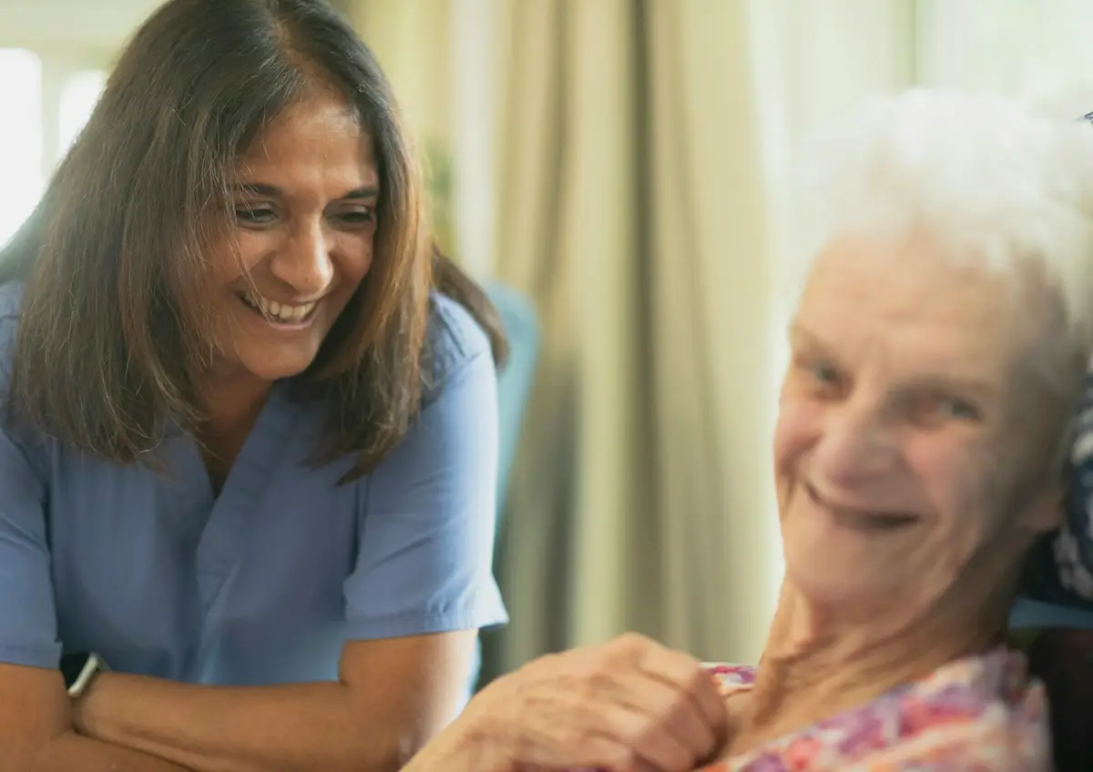 A carer sharing a warm smile with an elderly woman