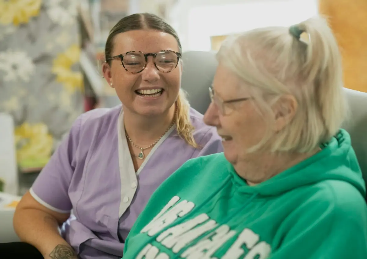 A carer laughing together with an elderly resident