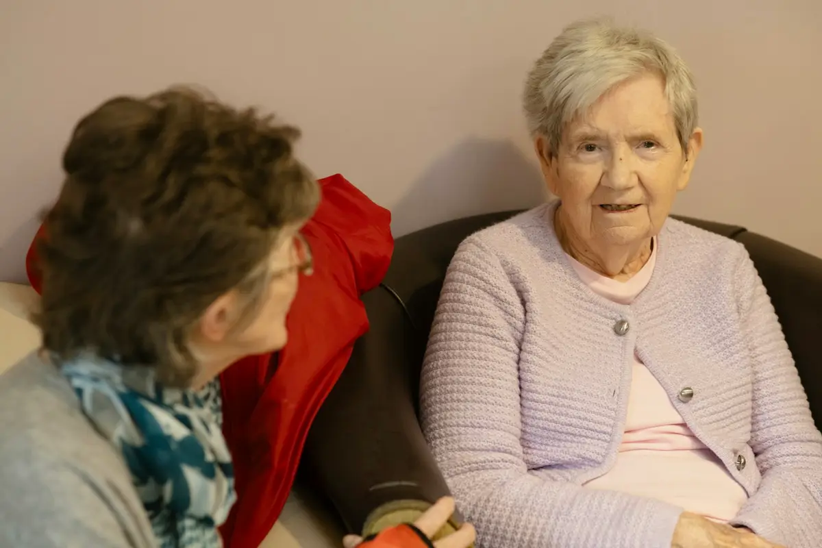 An elderly lady enjoying a conversation with a visitor