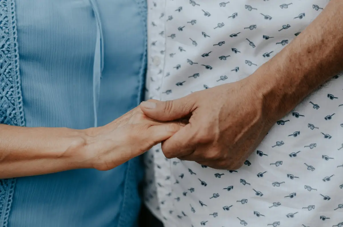 Two people gently holding hands