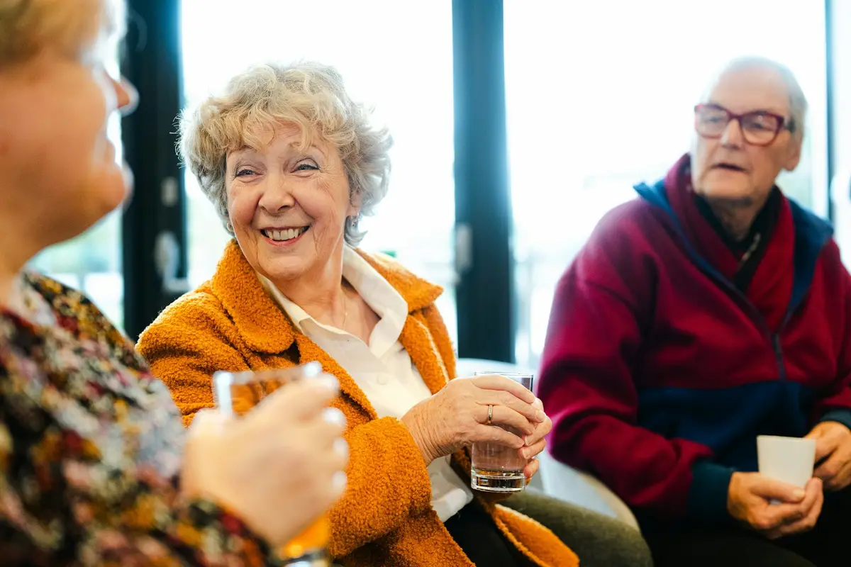 Elderly residents chatting and laughing together over drinks